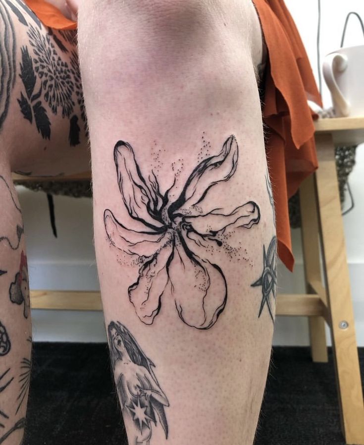 A Man S Legs With Tattoos On Them And Flowers In The Middle Of His Leg