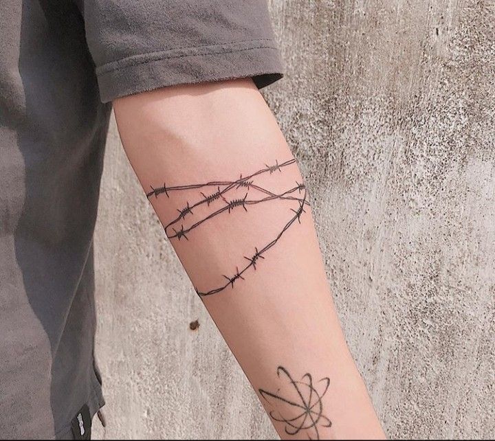 A Person With A Tattoo On Their Arm Has A Bird And Barbed Wire Behind It