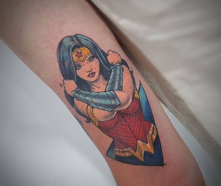 A Woman S Arm With A Tattoo On It That Has A Superman And Wonder Logo