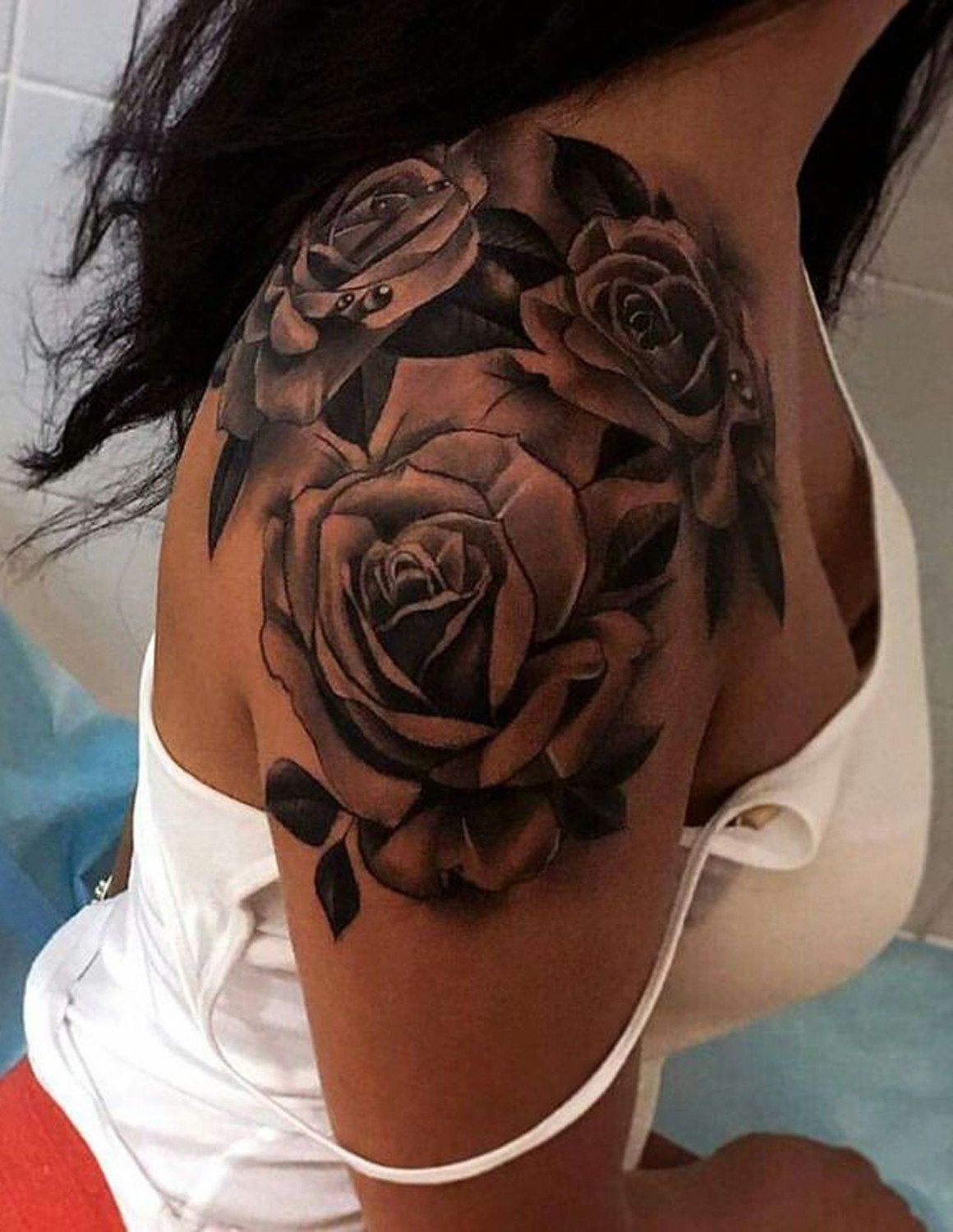 A Woman S Shoulder With A Rose Tattoo On The Left Side Of Her Chest