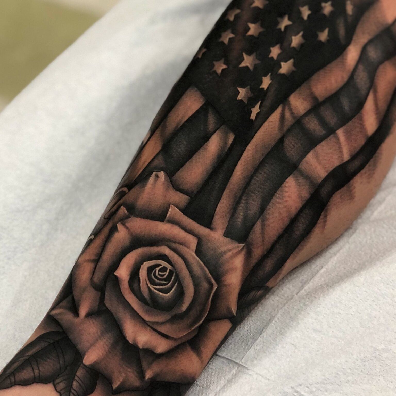 An American Flag With A Rose Tattoo On The Arm