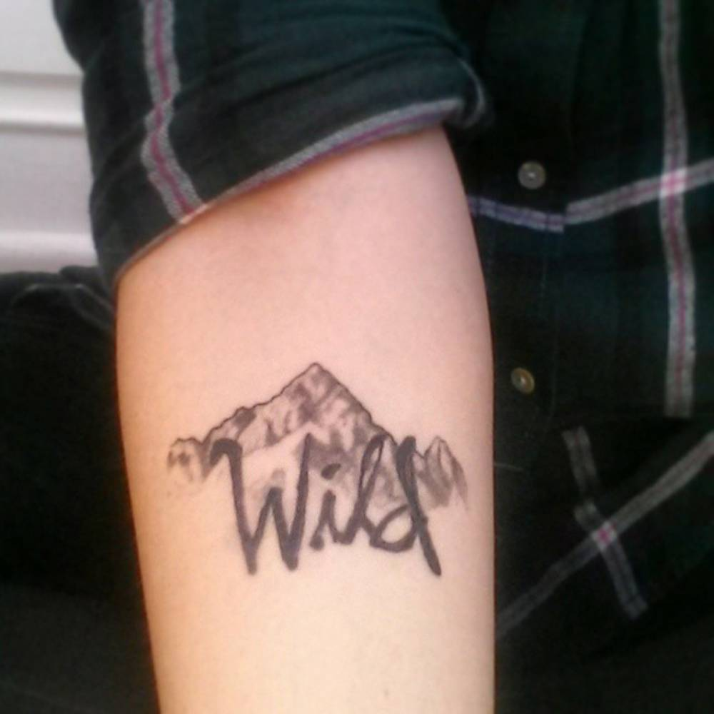 Forearm Tattoo Saying Wild Over A Mountain