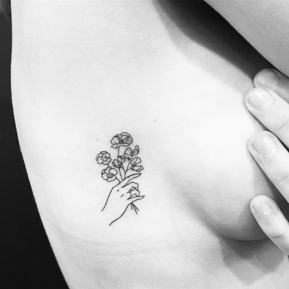 Minimalistic Hand Holding Flowers Tattoo Located On The