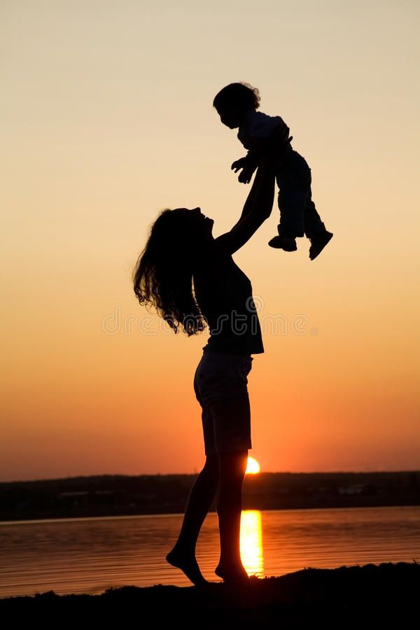 Silhouette Of Young Mother Hugging Toddler Son At Sunset Stock Photo By