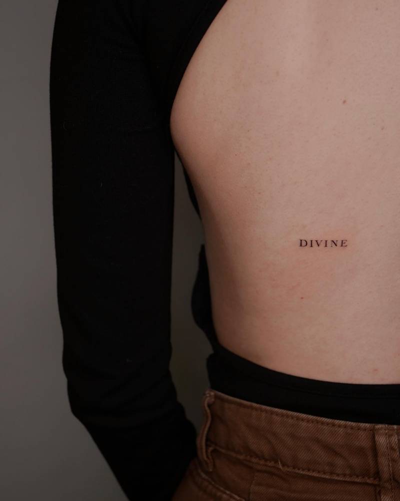 Tattoo Of The Word Divine Located On The Back